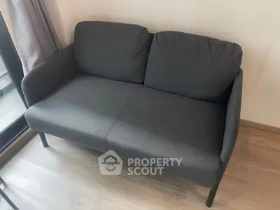 Cozy modern living room with stylish dark gray sofa and wooden flooring.