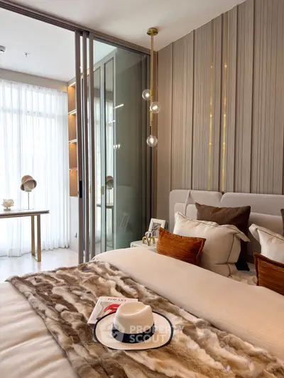 Luxurious bedroom with modern decor and natural light, featuring elegant pendant lighting and stylish furnishings.