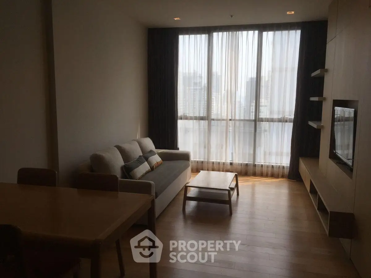 Modern living room with large windows and stylish furniture in a high-rise apartment.