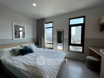 Modern bedroom with large windows and city view, featuring stylish decor and ample natural light.