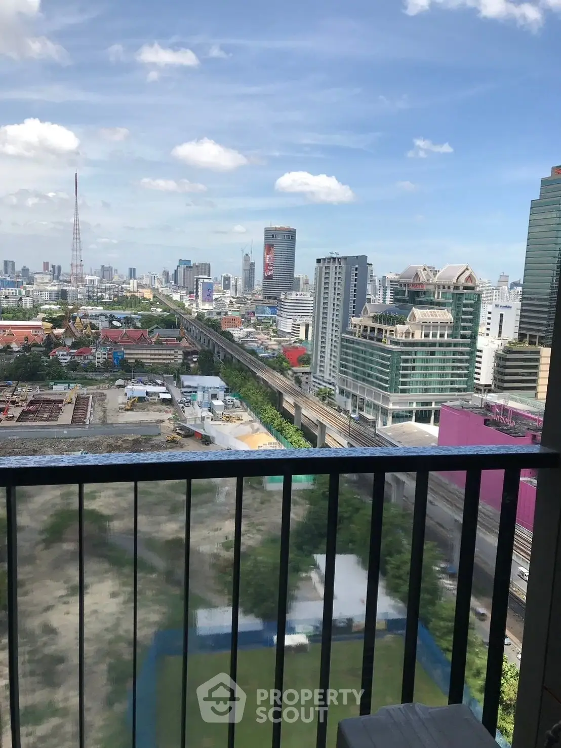 Stunning cityscape view from a high-rise balcony overlooking urban skyline and railway.