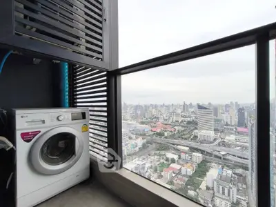 High-rise balcony with city view and washing machine, perfect urban living.