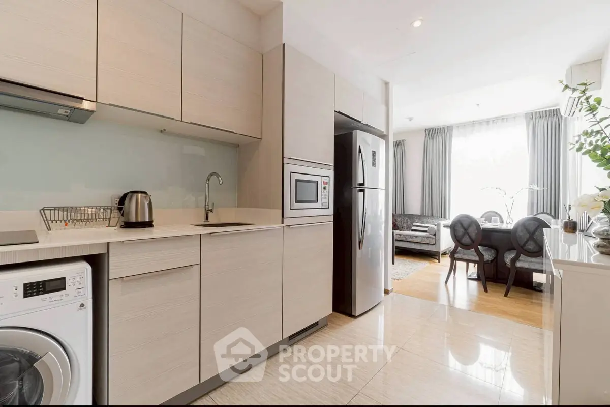 Modern kitchen with sleek appliances and open layout leading to elegant dining area.