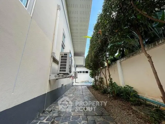 Charming side pathway with stone tiles and lush greenery in a modern home exterior.