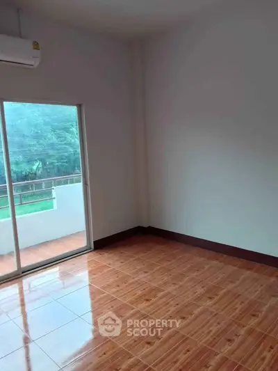 Spacious empty room with wooden flooring and balcony access