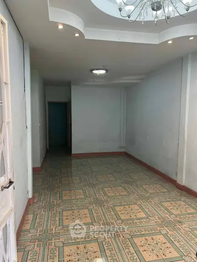 Spacious room with decorative tiled flooring and elegant ceiling light fixture.