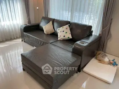 Spacious living room with modern leather sofa and large windows for natural light.