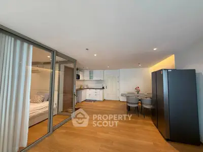 Modern open-plan living room with kitchen and dining area, featuring wooden flooring and sleek design.