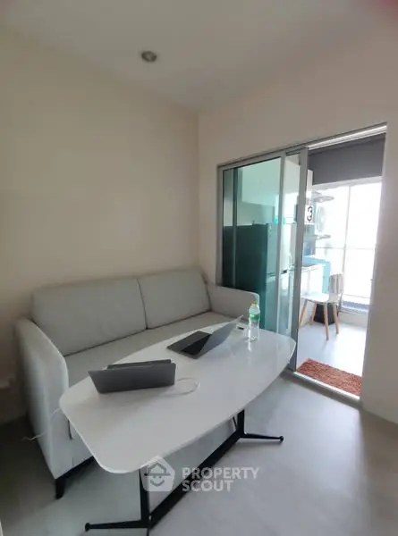 Modern living room with sleek sofa and table, featuring a bright balcony view.