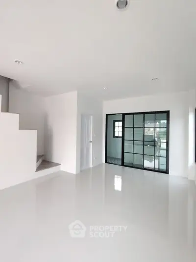 Spacious modern living room with sleek white flooring and large windows for natural light.