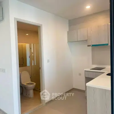 Modern apartment with compact kitchen and adjacent bathroom, ideal for urban living.