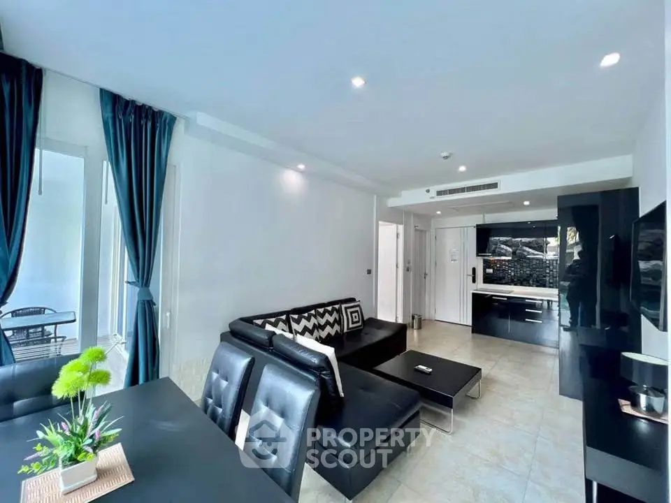 Modern living room with sleek black furniture and open kitchen layout in a stylish apartment.