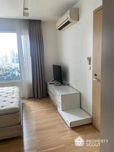 Modern bedroom with city view, featuring sleek furniture and air conditioning.