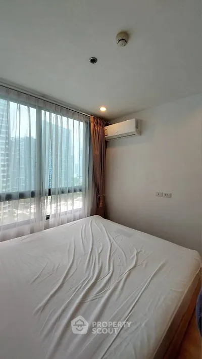 Modern bedroom with large window and city view, featuring air conditioning and natural light.