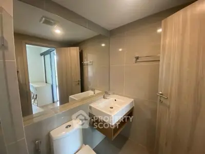 Modern bathroom with sleek fixtures and large mirror in contemporary apartment.