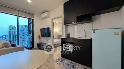Modern apartment with open kitchen and living area, featuring sleek black cabinetry and a city view balcony.