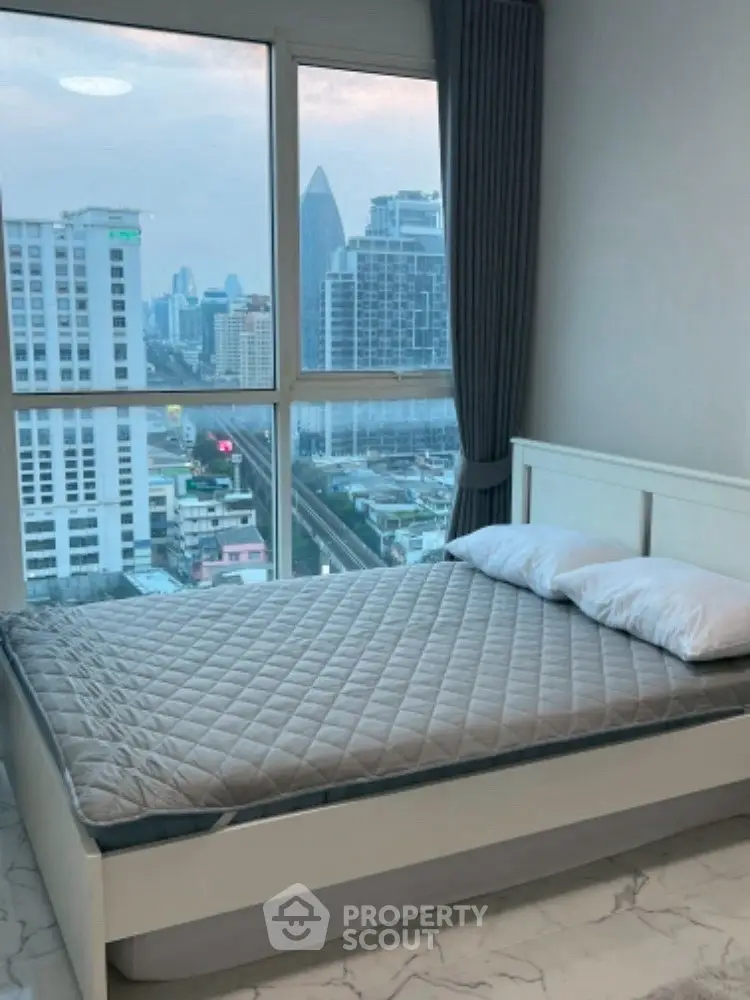 Modern bedroom with stunning city view from large window, featuring a cozy bed and elegant decor.