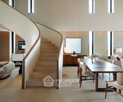 Luxurious open-plan living room with elegant staircase and modern dining area.
