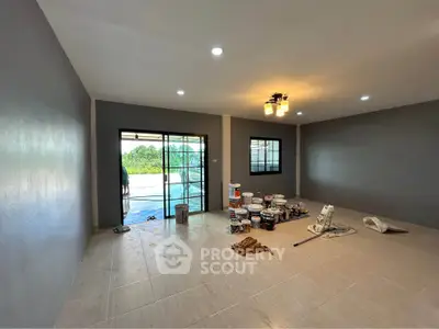 Spacious living room under renovation with modern lighting and large windows.