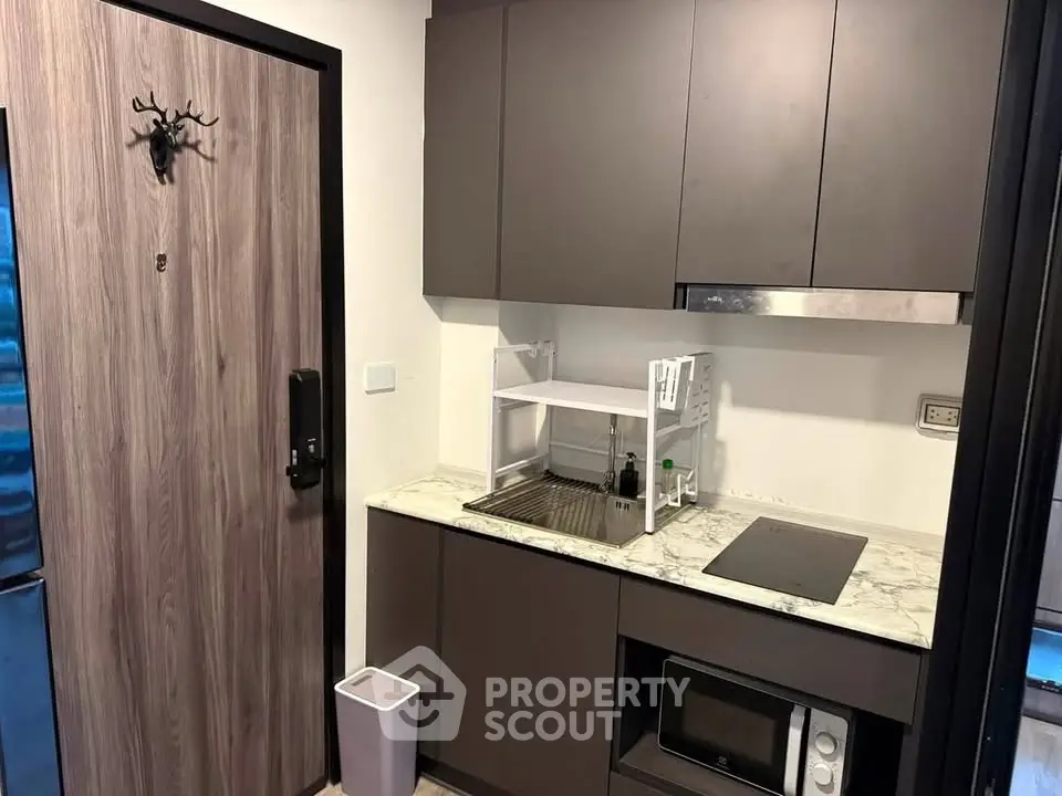 Modern compact kitchen with sleek cabinets and marble countertop in urban apartment.