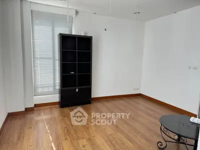 Spacious empty room with wooden flooring and large window, ideal for customization.