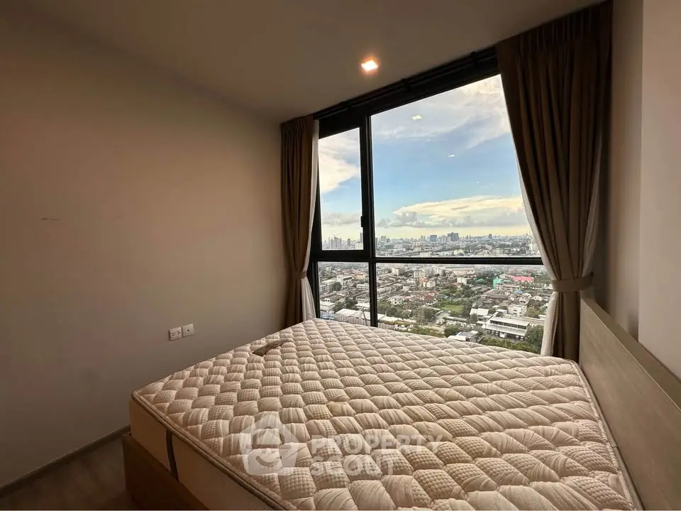 Spacious bedroom with stunning city view from large window, featuring a comfortable bed and elegant curtains.