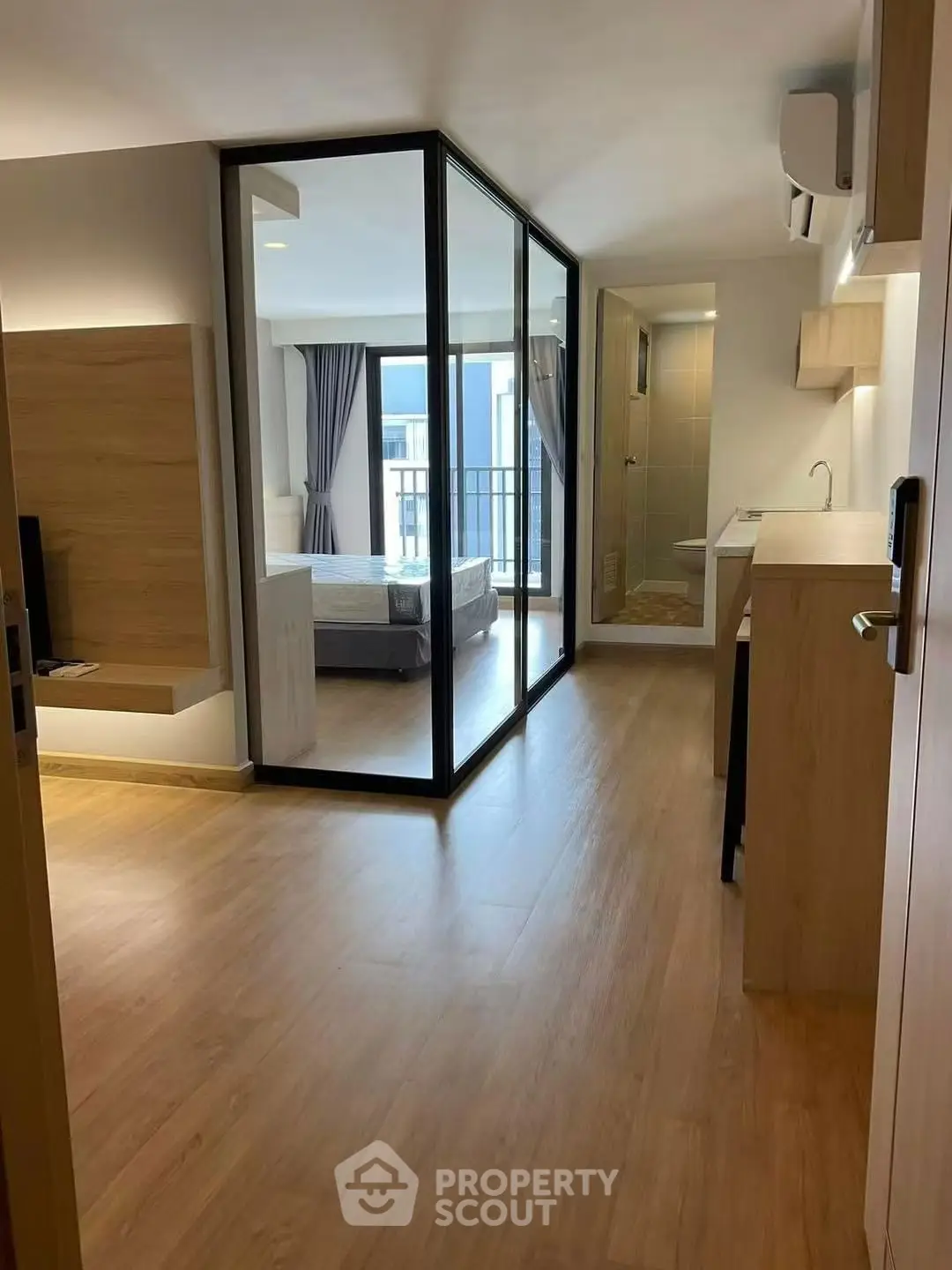 Modern open-plan apartment with glass partition and wooden flooring