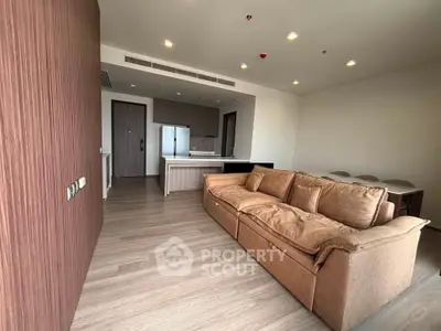 Spacious modern living room with open kitchen and stylish brown sofa in a contemporary apartment.