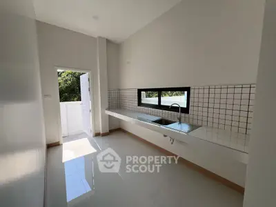 Modern kitchen with sleek design and outdoor access, featuring a large window and minimalist decor.