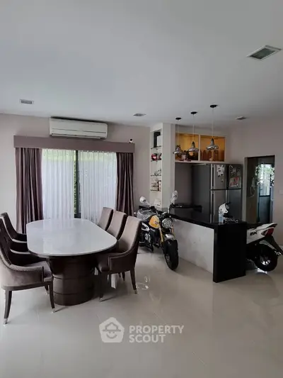 Modern dining area with elegant table and chairs, adjacent to a sleek kitchen with motorbikes parked indoors.