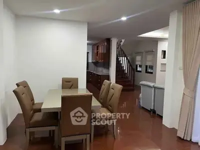 Spacious dining area with elegant table and chairs, leading to a modern kitchen and cozy living room.