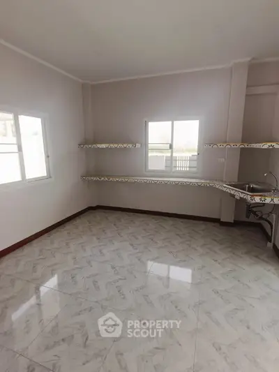 Spacious kitchen with tiled floor and ample natural light, featuring open layout and modern design.