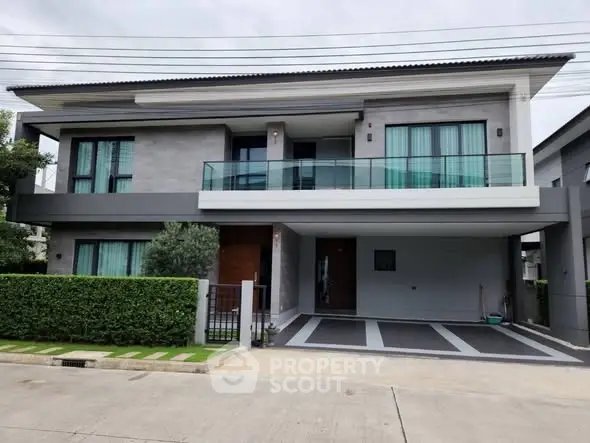 Modern two-story house with sleek design and spacious driveway in suburban neighborhood.