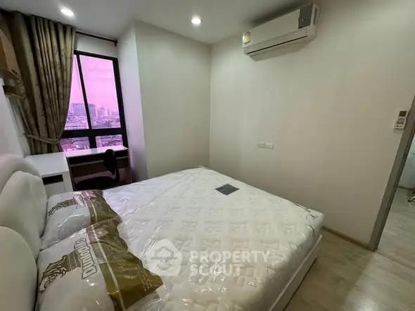 Modern bedroom with city view, featuring a comfortable bed and air conditioning, ideal for urban living.