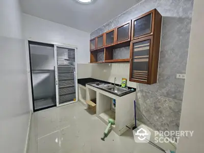 Compact modern kitchen with sleek white tiles, wooden cabinets, and built-in gas stove, perfect for urban living.