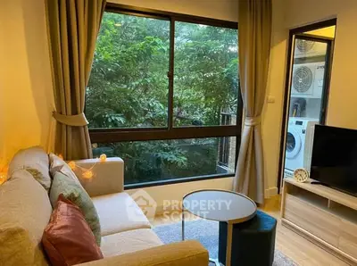 Cozy living room with large window and lush greenery view, featuring modern decor and washing machine.