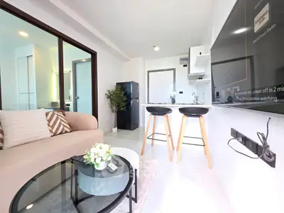 Modern living room with open kitchen, stylish decor, and cozy seating area in a bright apartment.
