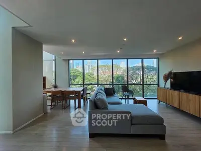 Spacious living room with large windows and modern furniture, offering a stunning city view.
