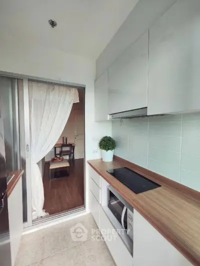Modern kitchen with sleek cabinetry and open layout leading to a cozy dining area.