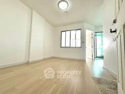 Spacious empty room with wooden flooring and bright natural light