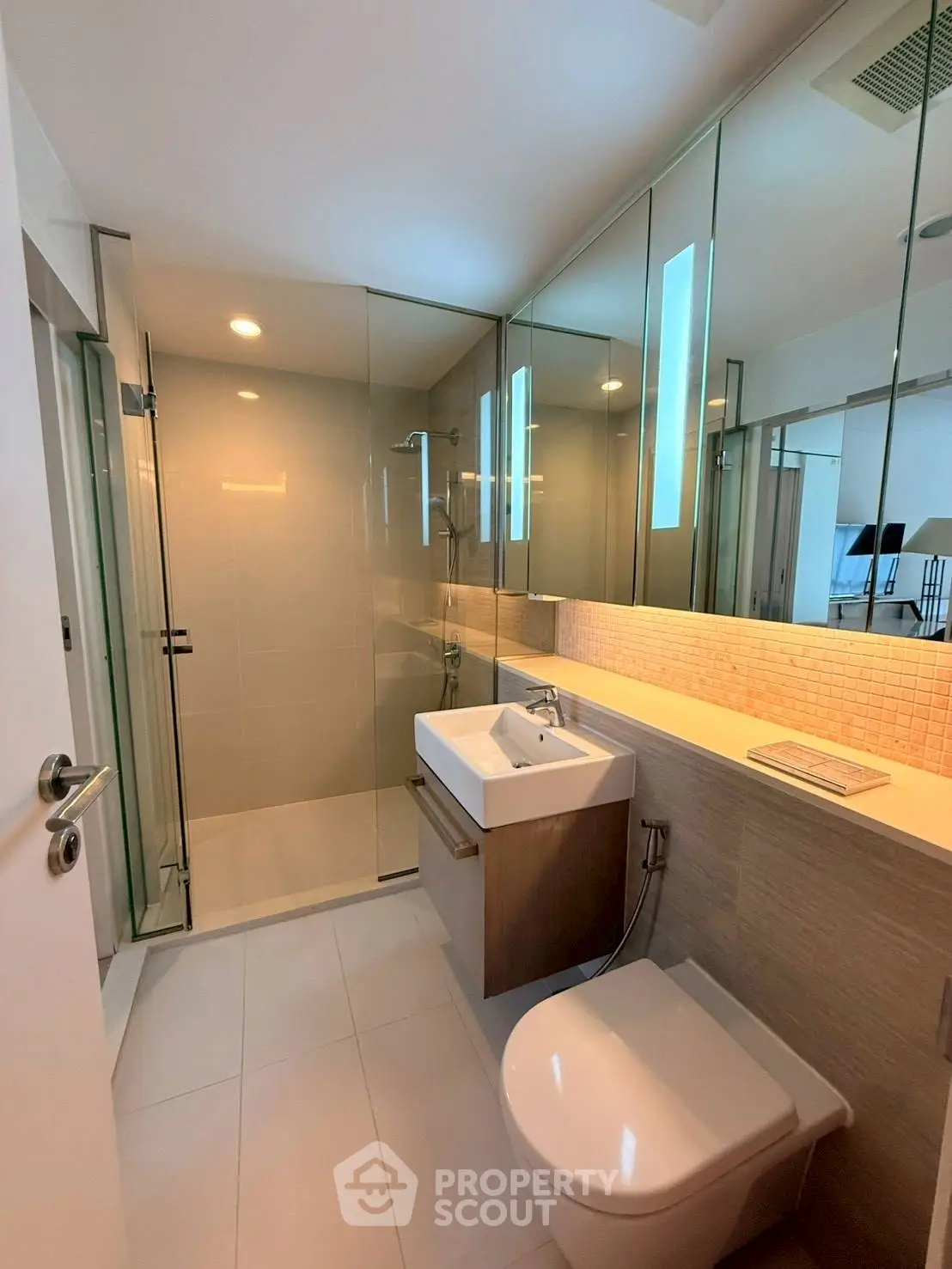 Modern bathroom with glass shower and sleek fixtures in contemporary apartment.
