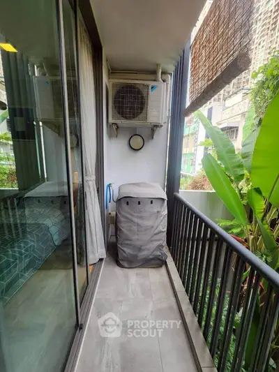 Compact balcony with air conditioning unit and lush greenery view