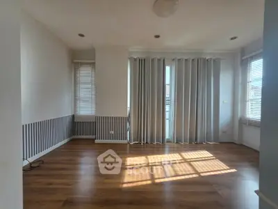 Spacious living room with large windows and wooden flooring, perfect for natural light lovers.