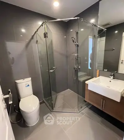 Modern bathroom with glass shower enclosure and sleek fixtures in a contemporary apartment.