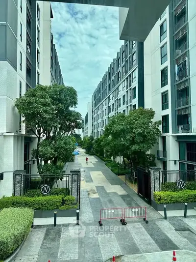 Modern apartment complex with lush greenery and spacious pathways.