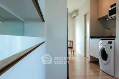 Modern apartment interior with sleek kitchen and washing machine, showcasing contemporary design and functionality.