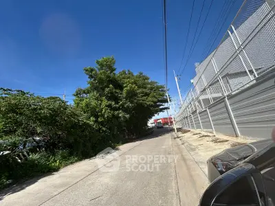 Explore this urban street view with lush greenery and modern fencing, perfect for future development opportunities.