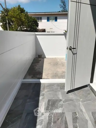 Modern outdoor patio with sleek tiled flooring and white privacy walls