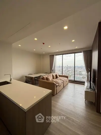 Modern living room with panoramic city view and sleek open kitchen.
