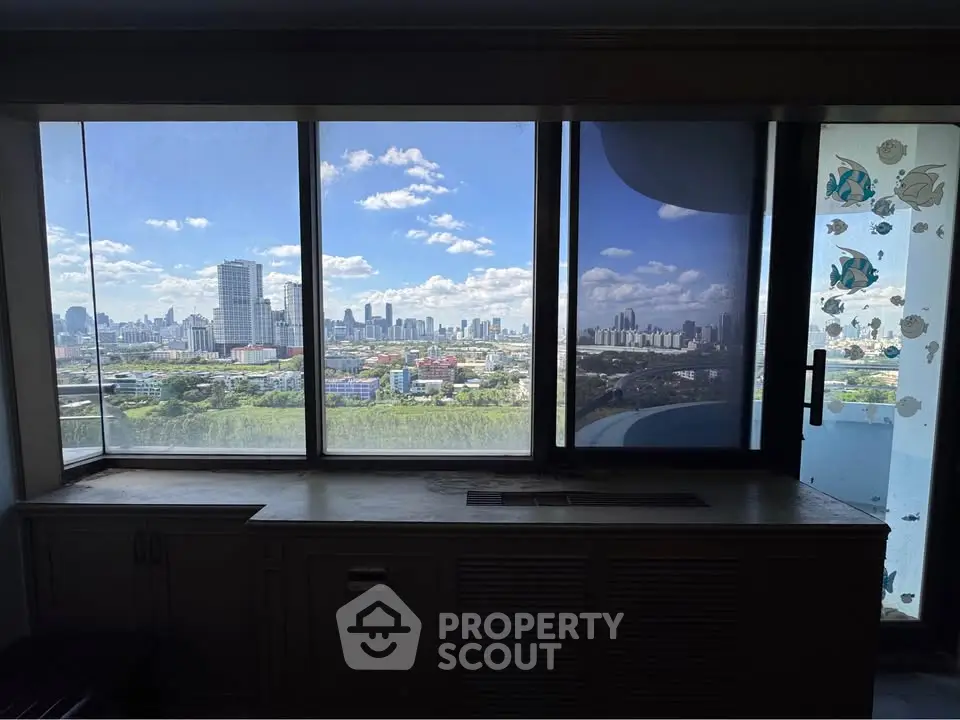 Stunning cityscape view from a high-rise apartment window with clear blue skies.